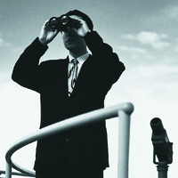 Man in dark suit looking through binoculars